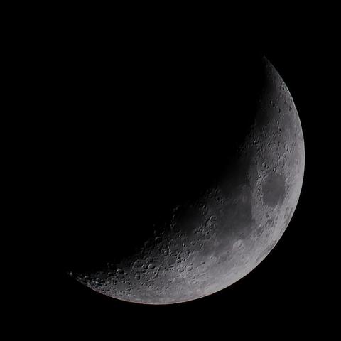 The Moon at waxing crescent phase on a dark background.