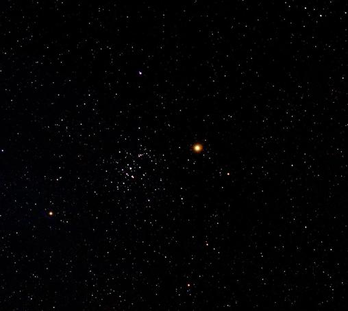 Bright planet Mars with the Beehive cluster of stars at centre. Many other star dots on a dark background.