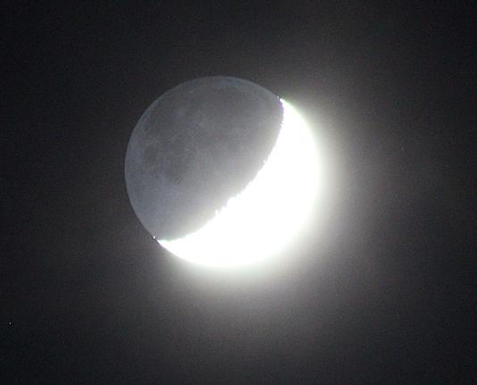 The Moon at waxing crescent phase with nightside illuminated by sunlight reflected from the Earth.