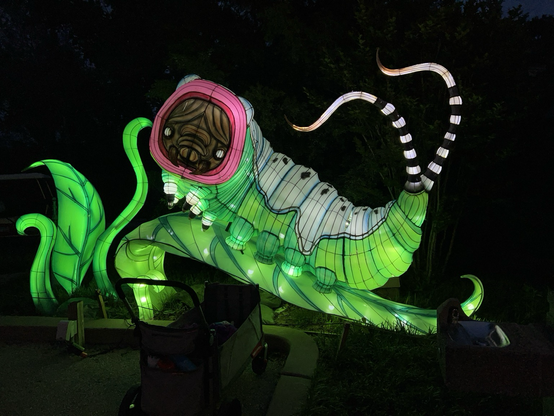 A mostly green and white, lit caterpillar with a sad face