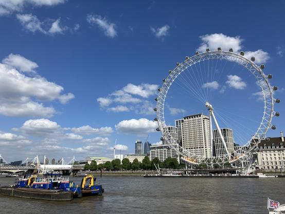 A dredging boat moored in the foreground of the River Thames, overlooking the London Eye from Westminster Embankment