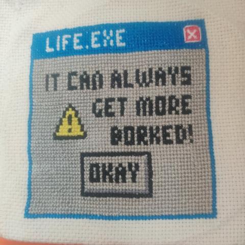 An cross stitch on off white monk's cloth. It looks a bit like a Windows XP error screen. There's a blue bar (9pts high) that has "life.exe" in white 5pt high text in it. There's also a red box with a white X in it. The red box has white backstitching around it.

The error box is grey, with a blue frame. It has a caution sign in it and the text "it can always get more borked" in 5pt font. Underneath the text is a centered button (for those who could count the stitches, it's actually slightly off centre because of evens and unevens!) that has the word "okay" in it.

The colours used in this piece are vibrant blue, vibrant red, vibrant yellow for the caution sign, black for text and button outline, and grey for the background. The button also has a slightly darker grey line for depth illusion, much like on a pc.