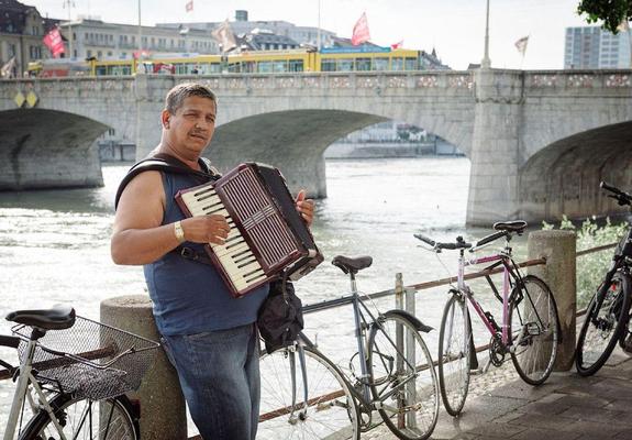 A musician plays in Kleinbasel, Switzerland, looking over the Rhine River to the Altstadt of Basel, Switzerland