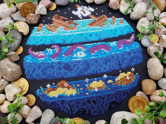 A cross stitch of layers of the sea. On the first layer, there is a shipwreck. On the second, there is a swarm of tentacles and some floating skulls. On the third is sparkling lost treasure.