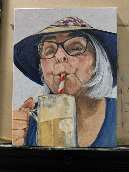 Old woman with gray hair, wearing a wide-brimmed hat and glasses, sucking on straw, enjoying a root beer float.