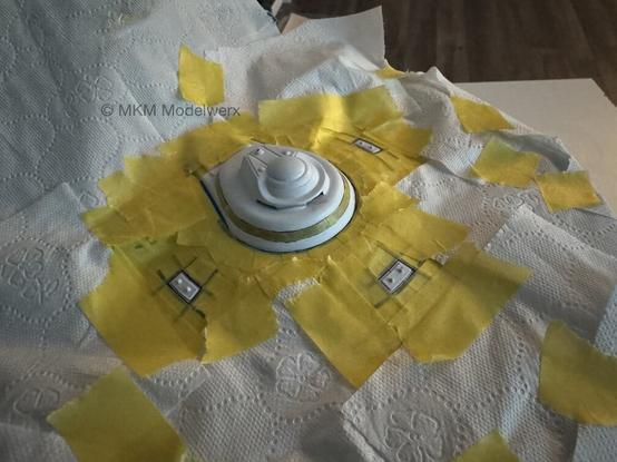 Top of the saucer covered with yellow masking tape and tissue paper leaving exposed the areas that need painted.