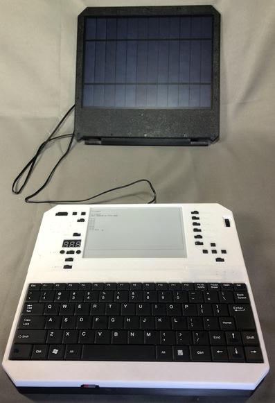 The image shows the Evertop, a portable retro PC featuring an E Ink display and hundreds of hours of battery life. It is a small electronic device equipped with a solar panel and a keyboard. The device is predominantly white with a black keyboard. The keyboard has a standard QWERTY layout with black keys and white lettering. Above the keyboard, there is an E Ink display showing a menu with text, and a digital display showing "8888." To the left of the screen, there are several buttons, including a numeric keypad and function keys. The solar panel, which also serves as the back-plate, is positioned above the device and is connected by a cable, suggesting it powers the device. The background is a plain, light-colored surface.