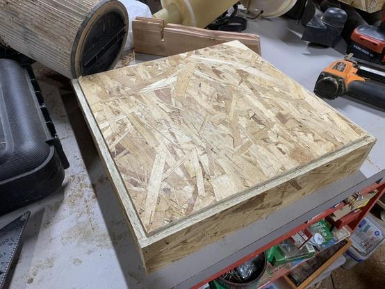 solid square of OSB being test fit in the top of the top frame