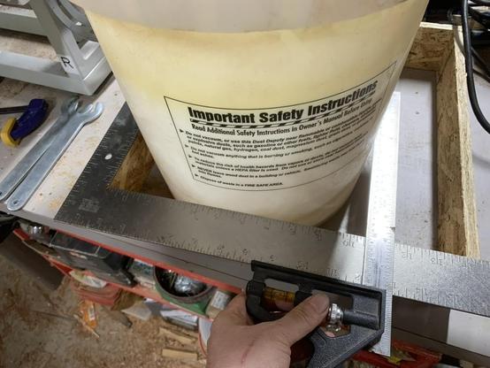 Using a framing square and a combination square as a sort of giant set of calipers to measure the diameter of the bucket