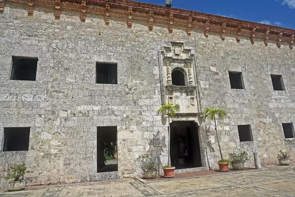 The image shows a historical stone building with a textured exterior. It features several windows and an ornate entrance, adorned with decorative elements. The architecture appears to reflect colonial or ancient styles, suggesting it may be a significant cultural or historical site. There's a clear blue sky above, indicating a bright, sunny day. Surrounding the entrance are potted plants, adding a touch of greenery to the scene.

Image Credits: Wikimedia / Mariordo (Mario Roberto Durán Ortiz) / CC BY-SA 4.0