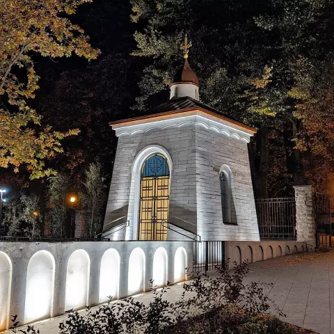 The image features a small, illuminated structure that appears to be a chapel or a monument, possibly located in a park or garden. It has a stone exterior with a decorative roof and a cross on top. The building is surrounded by trees and soft lighting, creating a serene night scene.

Image Credits: Wikimedia / ПринцШотландии / CC BY-SA 4.0