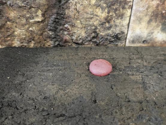 The silver has molten and formed a blob. The blowtorch has been removed but the silver is still glowing red.