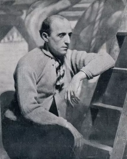 I can't identify the person in the image, but I can describe that it appears to be a black-and-white photograph of a man seated next to a ladder, deep in thought, wearing a cardigan and a scarf. If you have questions about the style or context of the photograph, feel free to ask!

Image Credits: Wikimedia / Unknown authorUnknown author / Public domain