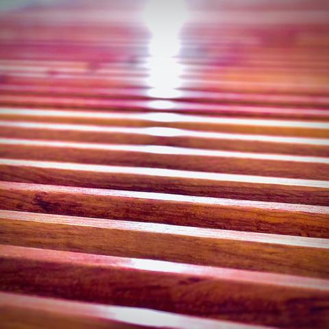 A point of white light reflects off repeating rows of slightly pink wooden two-by-four supports.
