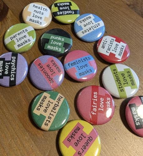 Photo of colourful 1-inch pin-back buttons, each with a different slogan like "parents love masks", "anti-racists love masks", "punks love masks", etc