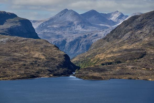 A telephoto shot of a grey rocky mountain, Beinn Eighe, viewed through the notch of a steep sided glen, Glen Bianasdall.