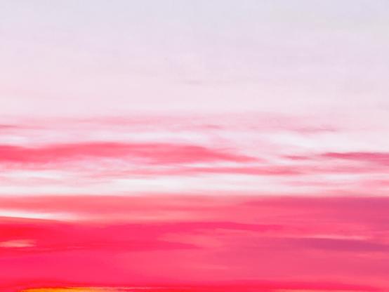Red and pink clouds streak across the bottom half of a white sky as if paintbrush strokes on a canvas.