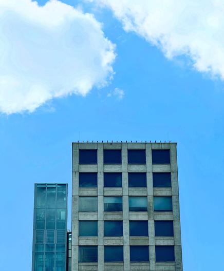 A modern building in front of a blue sky with fluffy clouds