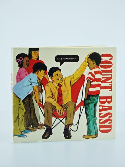 "Count Bass D - Act Your Waist Size." The album artwork features a cartoon illustration of a man sitting in a red folding chair, smiling and reaching out to touch the head of a young boy standing in front of him. The boy is wearing a red and white striped shirt and green jeans. Behind the seated man, three other children are looking on. One girl with a pink bow in her hair is wearing a pink shirt, another girl is wearing a red shirt, and a boy in a blue shirt is leaning forward with his hands on his knees. Above the seated man's head is a speech bubble that says, "Act Your Waist Size." The name "COUNT BASS D" is prominently displayed in large red letters vertically along the right side of the cover.