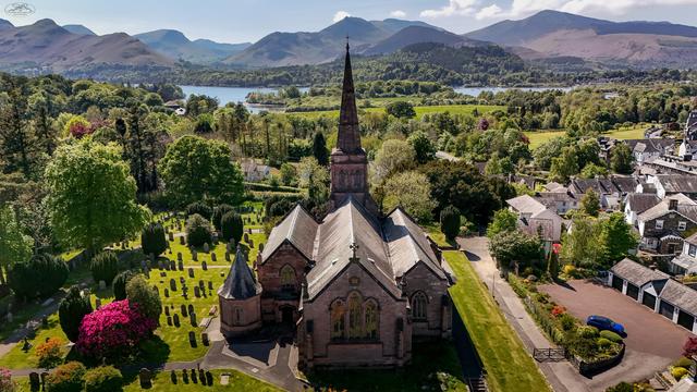 Church in vibrant green natural area, with views over lake and mountains in distance