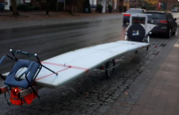 Ein Fahrradanhänger mit langen, hellen Kunststoffplatten.