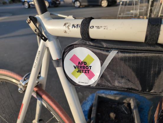 ein altes Rennrad mit einer Rahmentasche, auf der ein Aufkleber von afd-verbot.jetzt klebt