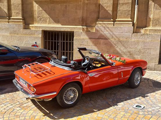 A red convertible car, branded for a wedding, parked next to Aix-en-Provence's city hall.