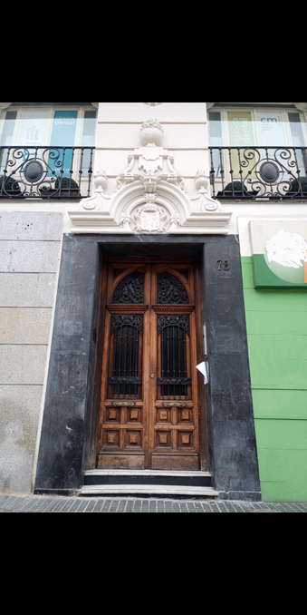A set of double wooden doors with an ornate metal grill that can be opened from inside, with decorative stone work and the number 78