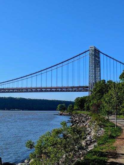 Bike/walk path along the Hudson river. The George Washington Bridge is in the background going over the river.