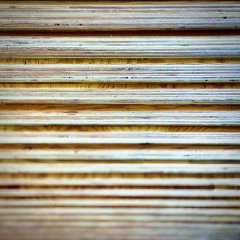 Horizontal slats of colorful multi-ply wood regress down from the foreground into the blurry distance.