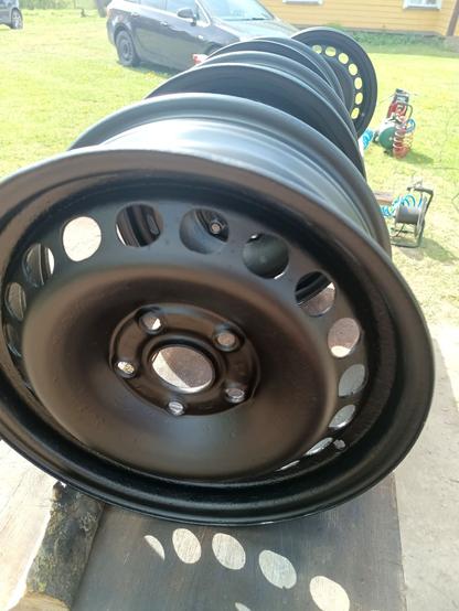 Opposite angle. Also shiny new paint. A cable drum and air compressor sit on the lawn next to a car.