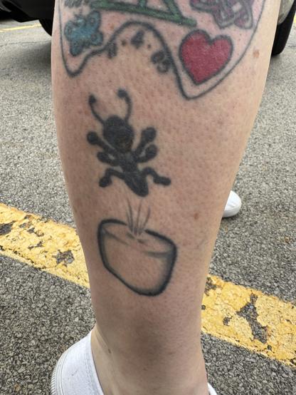 Black, mid side calf tattoo of an ant bouncing on a “white” marshmallow.