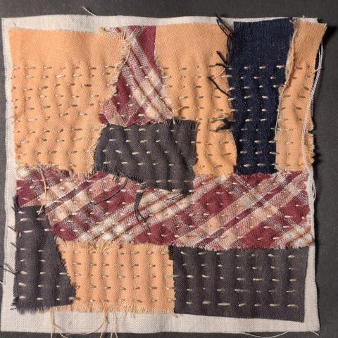 Ein paar Stoffschnipsel, die für eine Stoffcollage auf ein Stück Untergrundstoff aufgenäht werden.