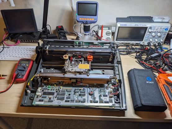 A partly disassembled IBM typewriter on an electronics workbench with various tools