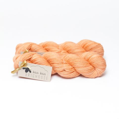 Picture shows two skeins of yarn, one in front of the other, in shades of orange.