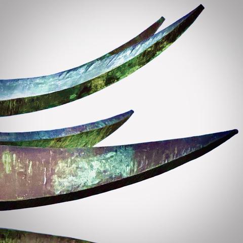 Several patina points of the large, sideways, metallic "Little Prince" crown art sculpture shine under an overcast sky.