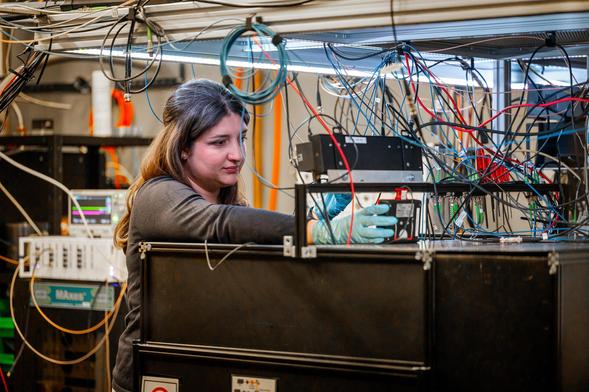 Postdoc Viviana Villafañe adjusts a complex experimental setup at the Walter Schottky Institute. Her research uses color centers in diamonds—atomic-scale defects with quantum properties—to explore how light, sound, and electron spin interact for future quantum technologies.