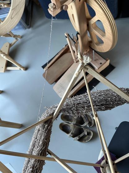 Swift with crinkled yarn and an Ashford Kiwi spinning wheel in the background with the yarn going into the orifice.