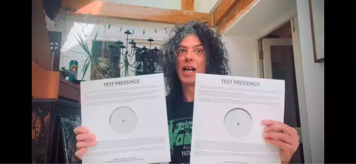 A curly headed gent holds two white records in his hands. Could it be the last Cardiacs album?