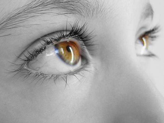 Closeup shot of a young girl eyes. The picture has been processed into monochrome except for the light brown colored eyes.