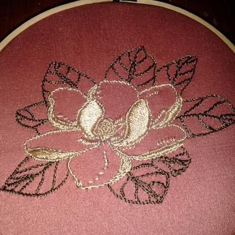 Hand-embroidered magnolia. The fabric is pink satin. The embroidery is done with beige and brown satin cotton threads.