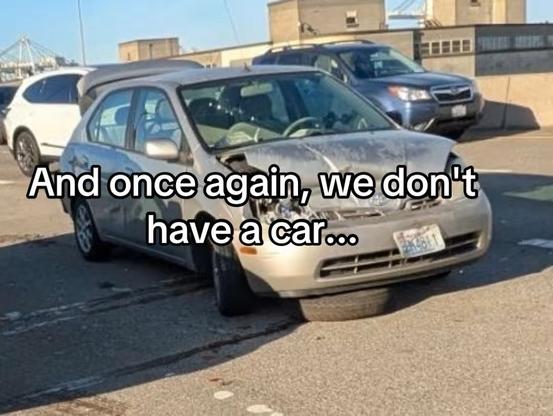 Image of a damaged silver car parked on the side of a road.

Text: And once again, we don't have a car...
