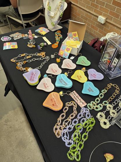A black cloth table with a bunch of larger than life heart dishes and glass chains with social media handles