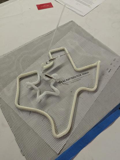A neon Texas on a screen on paper, white and off white tubes