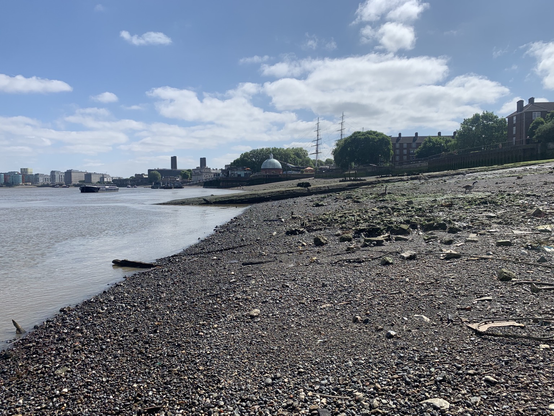 Low tide Thames with greenwhich foot tunnel building and cutty sark ship in the far background