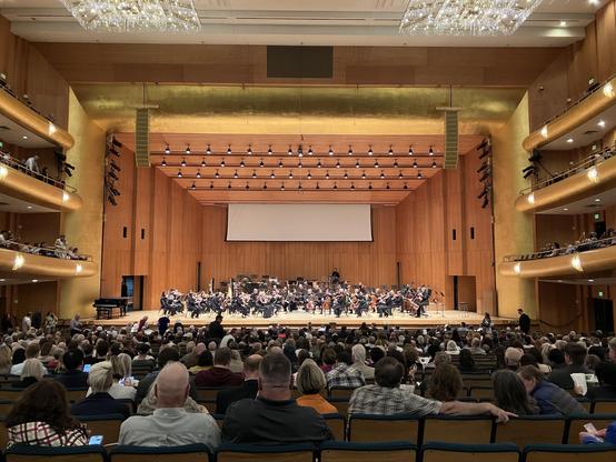A photo taken of the stage with orchestra members and surrounding seating with audience in Abravanel Hall in Salt Lake City, Utah just before a Utah Symphony concert.