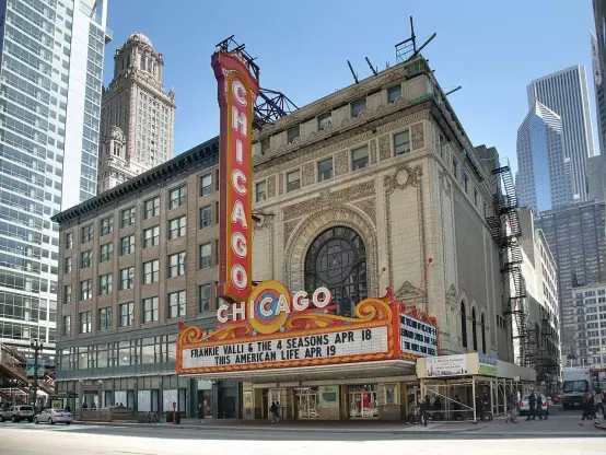 The image shows the Chicago Theatre, a historic and iconic venue located in Chicago, Illinois. The marquee displays upcoming events, and the building features distinctive architectural details, with a large sign highlighting the name "Chicago." Surrounding the theatre are tall modern buildings, showcasing the urban environment of the city.

Image Credits: Wikimedia / Daniel Schwen / CC BY-SA 4.0