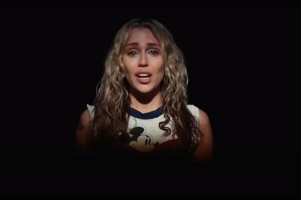 Screenshot Internet - Miley Cyrus, in einem Musikvideo - im Scheinwerfer-Spot singt, im Licht- und Schattenspiel.