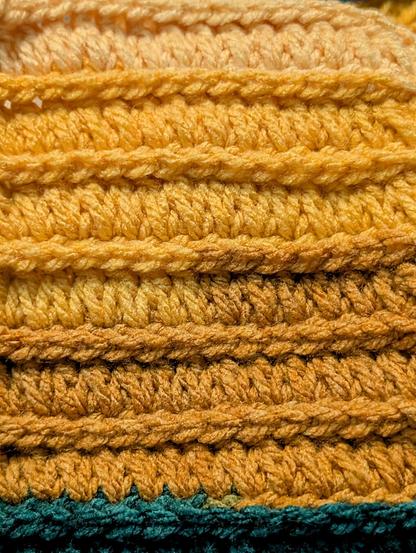 A close-up of one side of the crochet stitch I'm talking about. This is the side where the front post single crochet is very obvious. The yarn in the frame is a yellow ombre ending with a switch to dark green. I'm using a Caron Cinnamon Swirl cake in Sun & Surf.