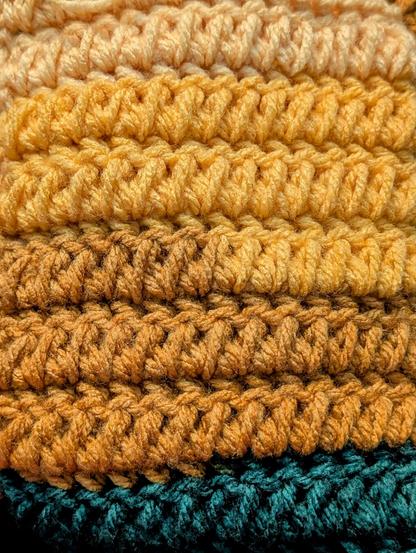 A close-up of one side of the crochet stitch I'm talking about. This is the side where the half double crochet together is the highlight. The yarn in the frame is a yellow ombre ending with a switch to dark green. I'm using a Caron Cinnamon Swirl cake in Sun & Surf.